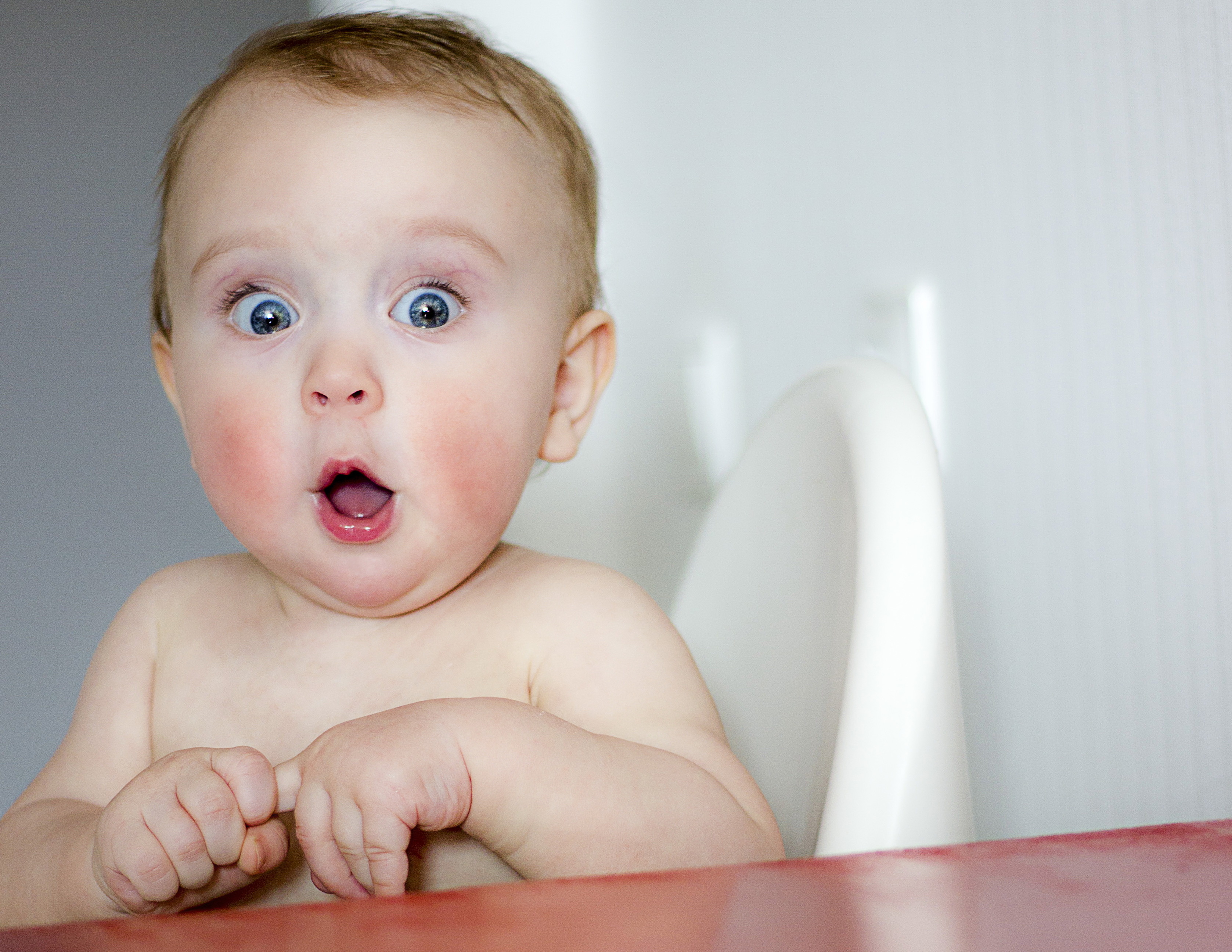 surprised kid sitting at table. child's eyes widened and mouth opened in amazement. copy space for your text